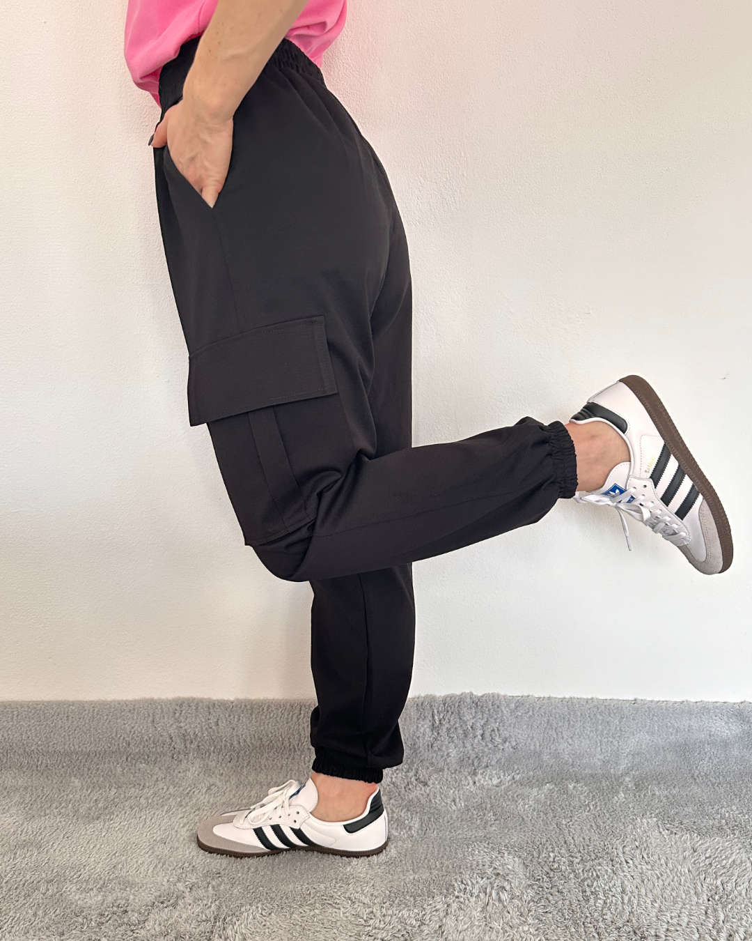 Unser Model trägt die Damen Army Cargopants in Schwarz. In der Einheitsgröße (von XS bis L). Mit einem Gummizug am Knöchel und an der Teile. Große Seitentaschen mit Funktionalität und Style. Alles auf ein Weißenhintergrund, Nella Fashion Online Shop
