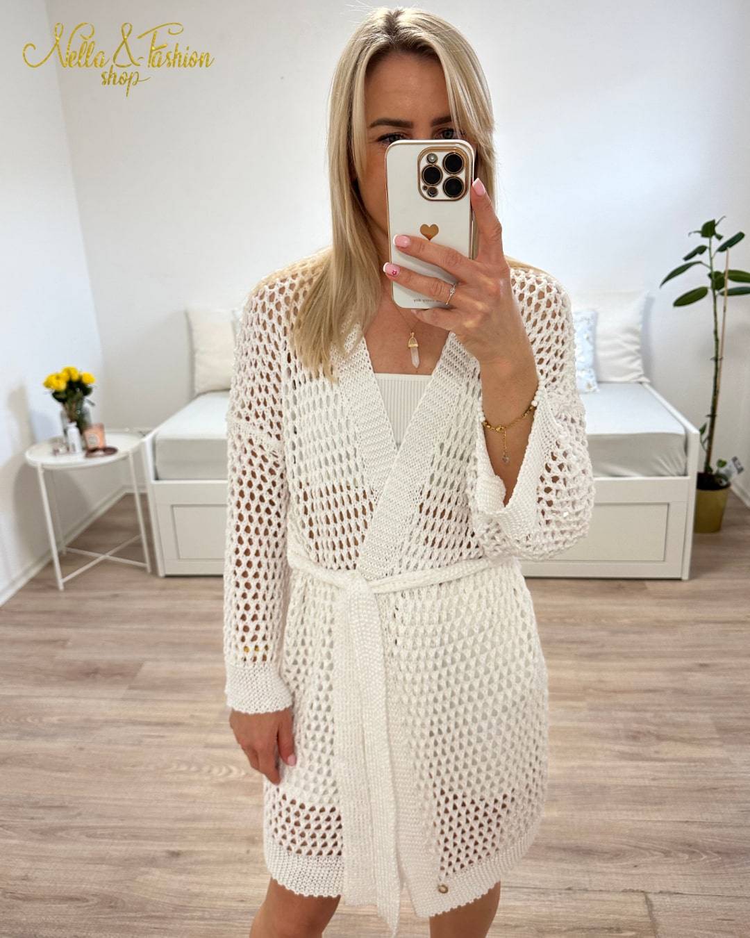 Model ist 160 cm groß und trägt ein weißen Langarm Cardigan, Einheitsgröße XS bis XL, Wickel mit Taillenbund, perfektes Strandkleid Knielänge, mit Lochmuster. Aus einer Mischung von 50 % Baumwolle und 50 % Acryl. Hintergrund Weiß. Nella Fashion Shop