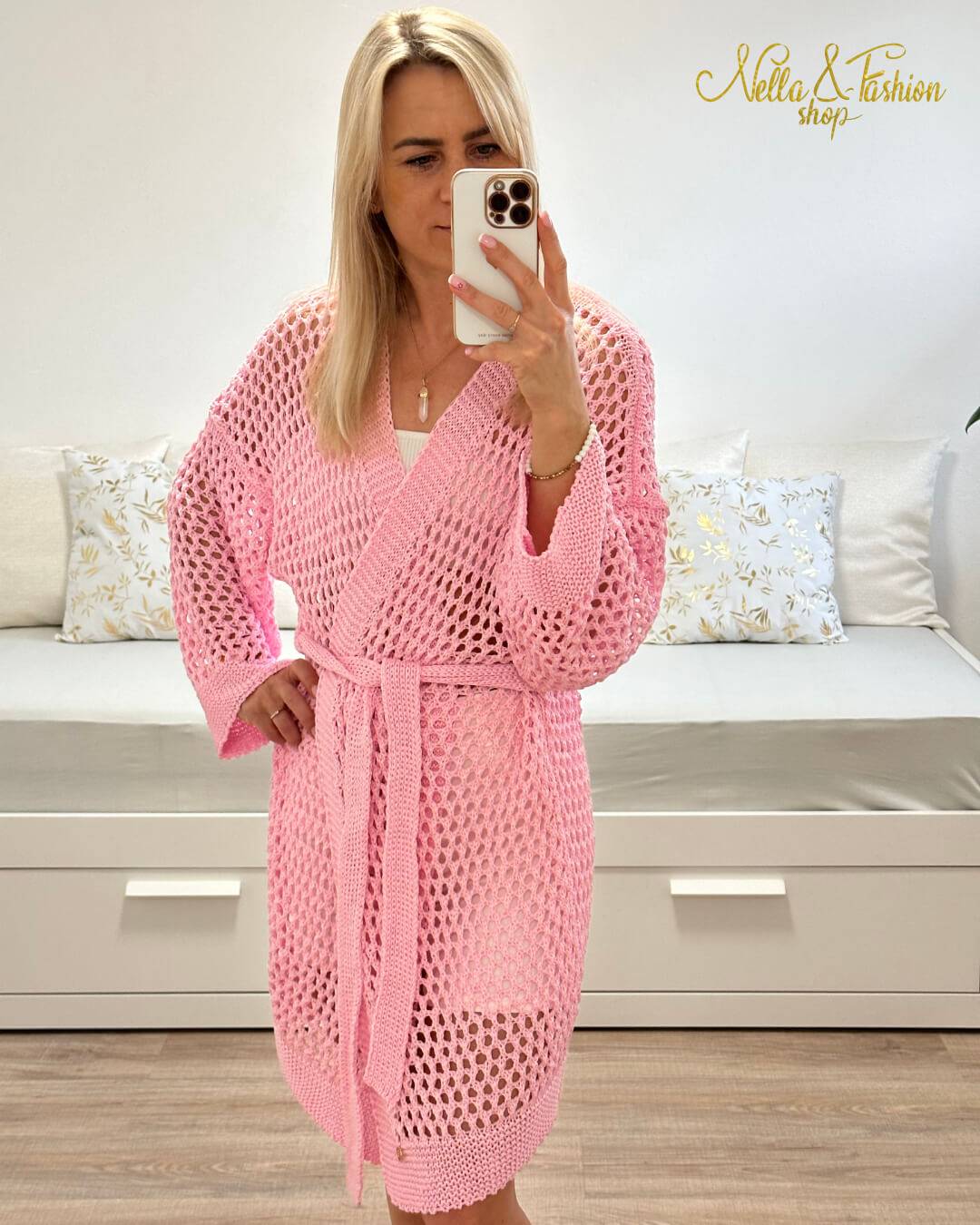 Model ist 160 cm groß und trägt ein Rosa Langarm Cardigan, Einheitsgröße XS bis XL, Wickel mit Taillenbund, perfektes Strandkleid Knielänge, mit Lochmuster. Aus einer Mischung von 50 % Baumwolle und 50 % Acryl. Hintergrund Weiß. Nella Fashion Shop