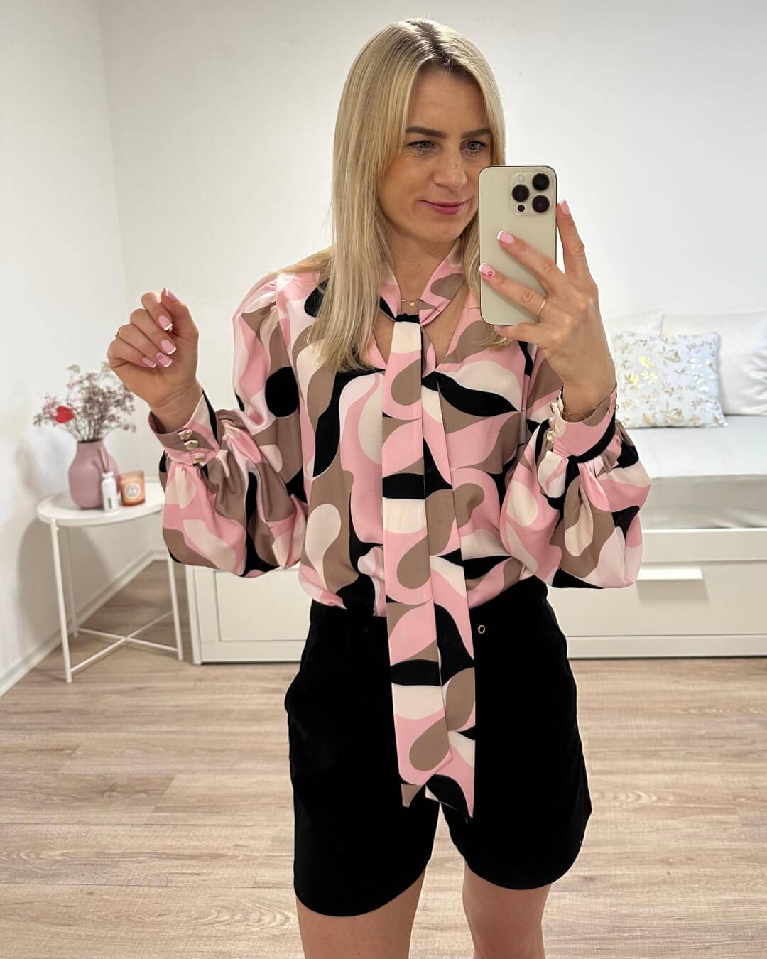 Model ist 160 cm groß und trägt Hemd mit V-Ausschnitt in Abstract mit Rosa-Weiß-Schwarz und Braunen Farben. Das Hemd ist Langarm mit Schleife am Hals, somit kann eine Krawatte gemacht werden. Alles auf ein Weißenhintergrund, Nella Fashion Online-Shop