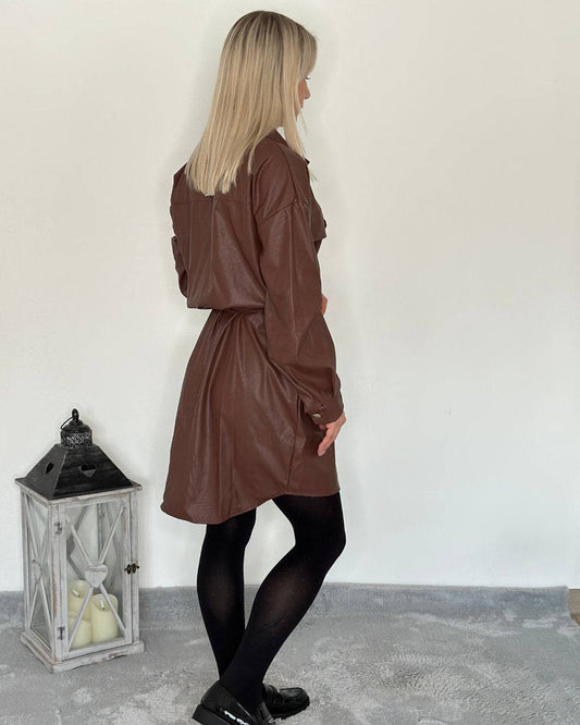 Model zeigt auf weißen Hintergrund das Kunstlederkleid in Schokoladenfarbe aus 95 % Polyester / 5 % Elastan von hinten. Detail ist der Gürtel aus dem gleichen Material in der Taille gebunden. Nella Fashion Shop