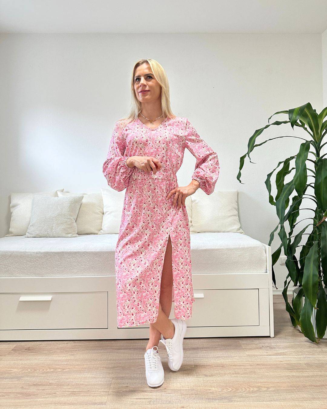 Model ist 160 cm groß und trägt das Knöchellanges elegantes Midi Kleid in Rosa mit Weißen Blumenmuster, mit V-Ausschnitt, Seitenschlitz und elastischen Gummibündchen an den Armen sowie in der Teile, aus 60 % Viskose, 35 % Polyester, 5 % Elasthan, alles auf ein Weißenhintergrund, Accessoires: Handtasche, Latschen, online kaufen bei Nella Fashion Shop