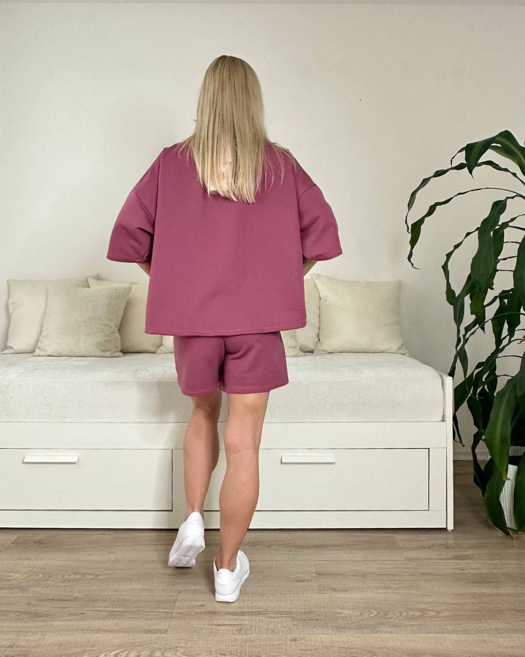 Model trägt den bequemen Damen lockeres Oversized T-Shirt mit weiten Armen in Beerenfarbe, Shorts mit Weißen Schnurdetail in Teile und Seitentaschen aus 95 % Baumwolle, 5 % Polyester, Set ist in Einheitsgroesse XS bis XL von Nella Fashion Shop