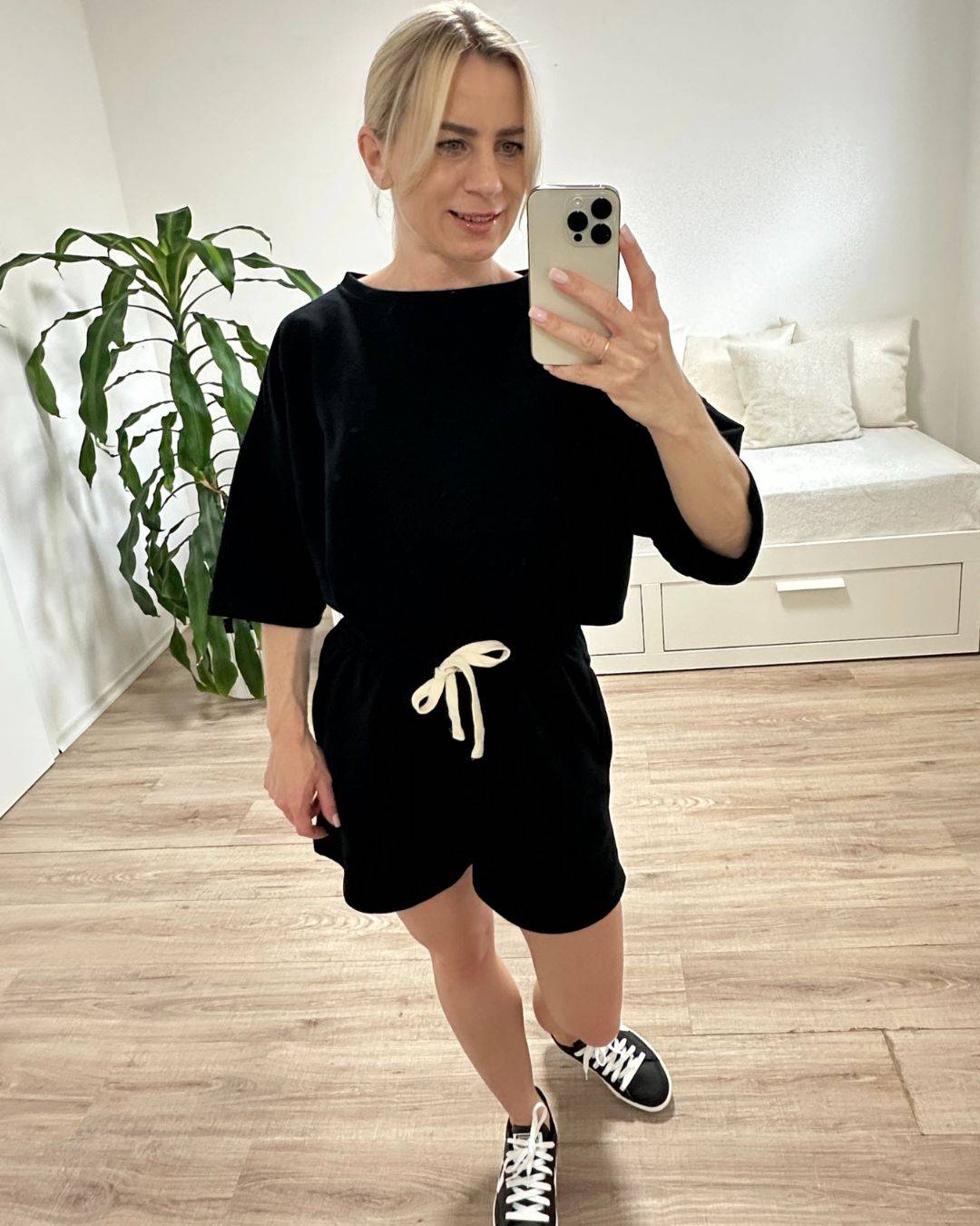 Model trägt den bequemen Damen lockeres Oversized T-Shirt mit weiten Armen in Schwarz, Shorts mit Weißen Schnurdetail in Teile und Seitentaschen aus 95 % Baumwolle, 5 % Polyester, Set ist in Einheitsgroesse XS bis XL von Nella Fashion Shop
