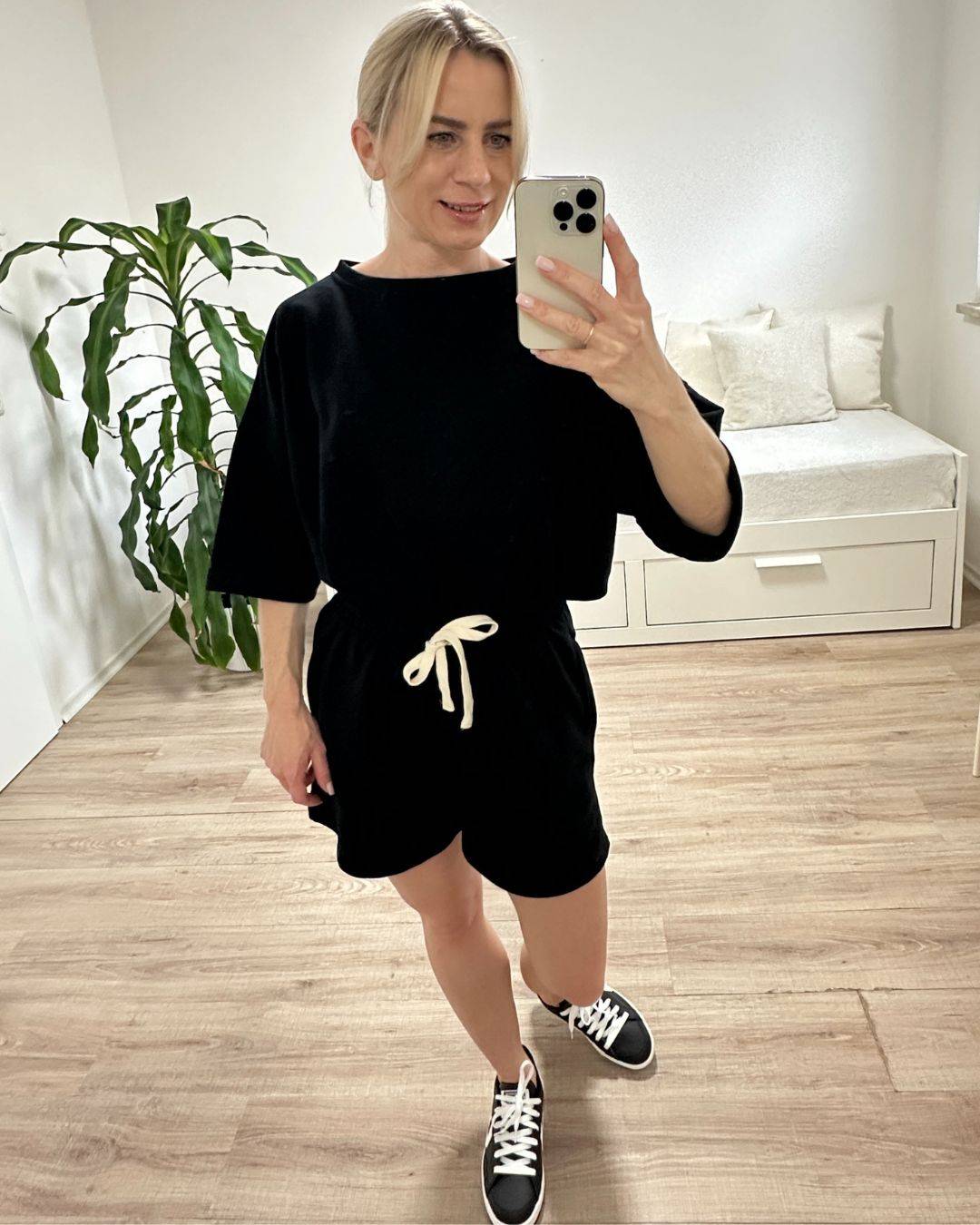 Model trägt den bequemen Damen lockeres Oversized T-Shirt mit weiten Armen in Schwarz, Shorts mit Weißen Schnurdetail in Teile und Seitentaschen aus 95 % Baumwolle, 5 % Polyester, Set ist in Einheitsgroesse XS bis XL von Nella Fashion Shop