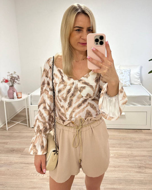 Model präsentiert Damen Sommeroutfit spanische Damenbluse Langarm in Beige Zebra-Muster mit Hoch taillierte Damenshorts in Beige Einheitsgröße von XS bis L, mit elastischem Bund (Gummiband) in der Taille und einer goldenen Schnur zuzüglich Seitentaschen. Shorts sind aus 95 % Polyester / 5 % Elastan Mischung. Hintergrund Weiß. Jetzt bei Nella Fashion Shop Deutschland