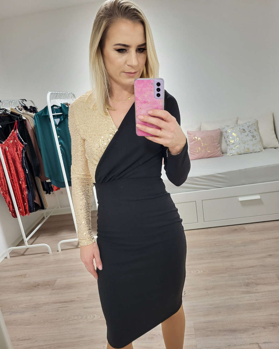 Model trägt auf einem weißen Hintergrund das sehr enge schwarze Bleistiftkleid mit Golden Pailletten am rechte Schulter aus 70 % Baumwolle / 12 % Polyester / 18 % Lycra zuzüglich mit einem praktischen Reißverschluss am Rücken. Erhältlich in Größe S, M, L und XL bei Nella Fashion Shop 
