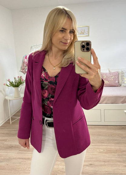 Model präsentiert ein klassischer Damen-Blazer Slim fit kurz, schmal, mit Puffärmeln einreihiger in der Farbe Fuchsien. Blazer hat vorne 2 Taschen. Jetzt bei Nella Fashion Shop in Größe S oder M. Kombiniert mit Weißen Hosen und spanische Damenbluse perfekter outfit. Jetzt bei Nella Fashion Shop 