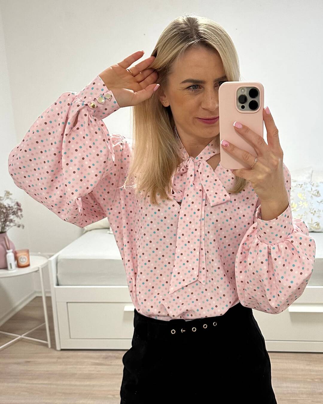 Model hat das Langarm-Hemd in Rosa zuzüglich mit bunt gepunktetes Muster. Das Hemd ist Langarm mit Schleife am Hals, somit kann eine Krawatte gemacht werden. V-Ausschnitt und weiten Armen. Alles auf ein Weißenhintergrund, Nella Fashion Online Shop   