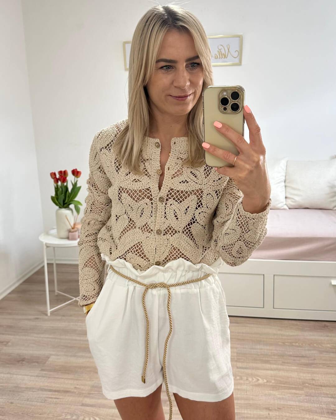 Model hat den Damen Boho Pullover in Biege mit weißen hoch taillierte Damenshorts in Einheitsgröße von XS bis L, mit elastischem Bund (Gummiband) in der Taille und einer goldenen Schnur zuzüglich Seitentaschen. Hintergrund Weiß. Jetzt bei Nella Fashion Shop Deutschland