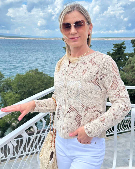 Das Model ist 160 cm groß und präsentiert die Damen Boho Rundhals Strickpullover aus 100 % Baumwolle in Beige und Größe S/M mit Holzknöpfen Verschluss. Hintergrund ist ein Meer der kroatischen Küste der Adria. Nella Fashion Shop 
