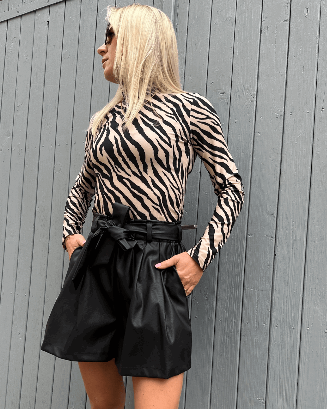 Das Model präsentiert Damen Herbst Outfit Kunstleder Shorts Schwarz in XS mit Damen Rollkragenpullover Zebramuster S, Nella Fashion Shop  
