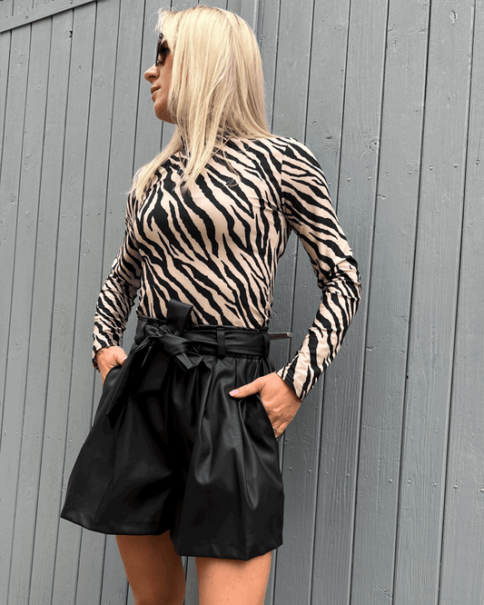 Das Model präsentiert Damen Herbst Outfit Kunstleder Shorts Schwarz in XS mit Damen Rollkragenpullover Zebramuster S, Nella Fashion Shop  