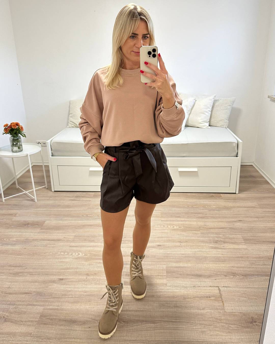 Model ist 160 cm und trägt unsere Damen Kunstleder Shorts in Schokoladenfarben Größe 34 aus 95 % Polyester / 5 % Elastan und eine Schleife/Gürtel kombiniert mit Oversized Sweatshirt XXL perfektes Herbst Outfit für Frauen, auf Weißen Hintergrund, Nella Fashion Shop