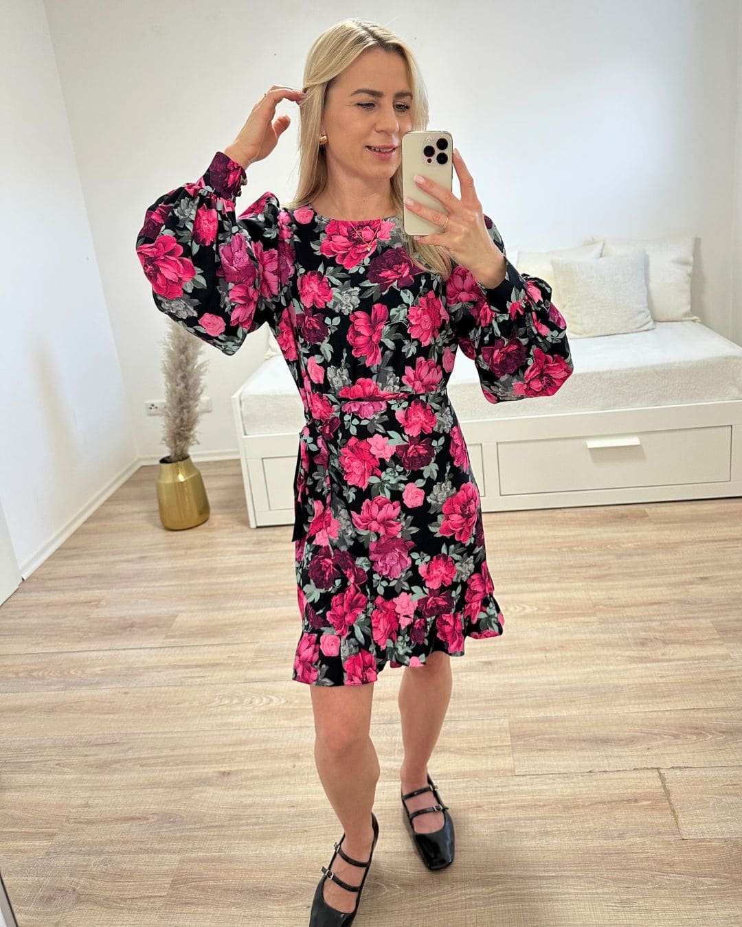 Model präsentiert das Wickel Mini Kleid MARBELLLA in Blumenmuster aus Materialmix von 70 % Viskose und 30 % Polyester. Praktischer Reißverschluss am Rücken und Bindung mit einem Stoffgürtel in der Taille. Foto auf weißen Hintergrund. Nella Fashion Shop 