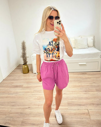Model präsentiert das Weiße Kurzarm T-Shirt mit Print dazu unseren Minirock im Weiß auf ein Weißenhintergrund, perfektes Sommerlook für Urlaub, Strand oder Unterwegs, jetzt online bestellen bei Nella Fashion Shop 