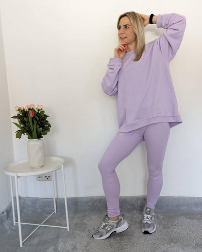 Model präsentiert das Damen Oversized Sweatshirt in der Einheitsgröße von XS bis L mit gerippten dehnbaren Push-up-Leggings mit hohem Bund in XS/S und M/L Größe.  In Hell Lila Trendfarbe, auf ein Weißen Hintergrund, Nella Fashion Shop