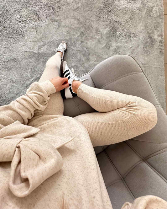Das Model hat die beige gerippten dehnbaren Leggings aus 95 % Baumwolle / 5 % Elasthan mit Gummi in der Teile. Sie bieten einen bequemen, eleganten und sportlichen-look für den Alltag. Alles auf ein Weißenhintergrund, Nella Fashion Online Shop   