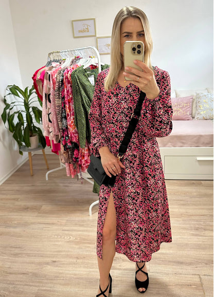 Model ist 160 cm groß und trägt das S/M Knöchellanges elegantes Midi Langarm-Kleid in Schwarz mit Punktenmuster, mit V-Ausschnitt, Seitenschlitz und elastischen Gummibündchen an den Armen sowie in der Teile, aus 60 % Viskose, 35 % Polyester, 5 % Elasthan, alles auf ein Weißenhintergrund, Accessoires: Schuhe, Tasche, Handy, online kaufen bei Nella Fashion Shop Deutschland