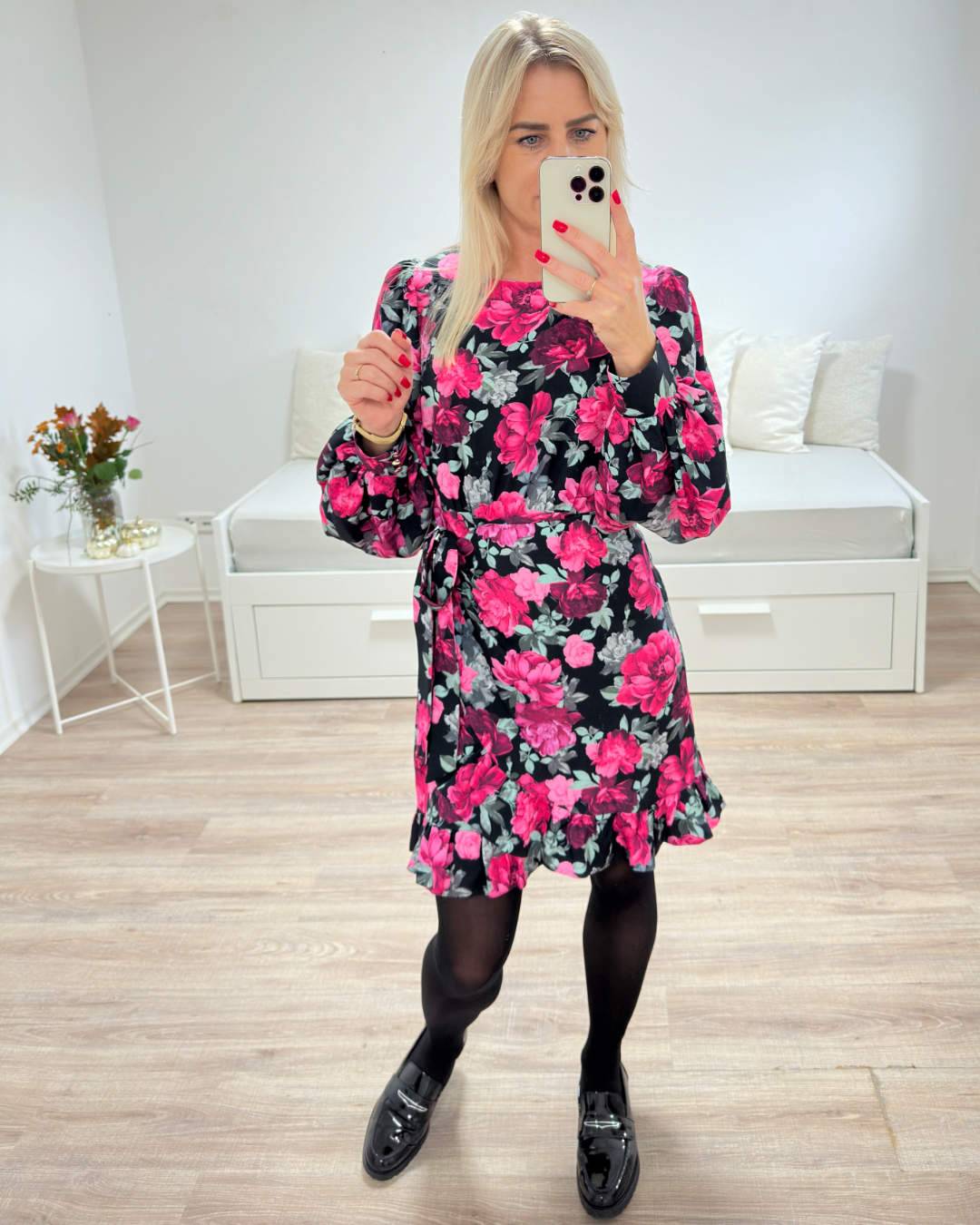 Model hat das Damen-Wickelkleid MARBELLLA in der Größe S an. Die Rosen Blumen Muster Mini Kleid, ist Rundhalsausschnitt und Langarm. Erhältlich in Größen S, M oder L bei Nella Fashion Shop Deutschland und aus 70 % Viskose und 30 % Polyester. Foto auf weißem Hintergrund. 
