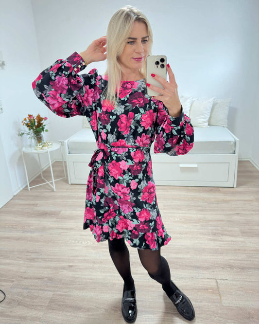 Model ist 160 cm groß und präsentiert Damen Mini Kleid MARBELLLA mit Rosen, Blumen Muster in der Größe S und praktischer Reißverschluss am Rücken. Mit langen, weiten Ärmeln und Bindung mit einem Stoffgürtel in der Teille verleiht dezent die Weiblichkeit. Das Blumendamenkleid wird beendet, mit Rüsche. Foto auf weißen Hintergrund. Nella Fashion Shop