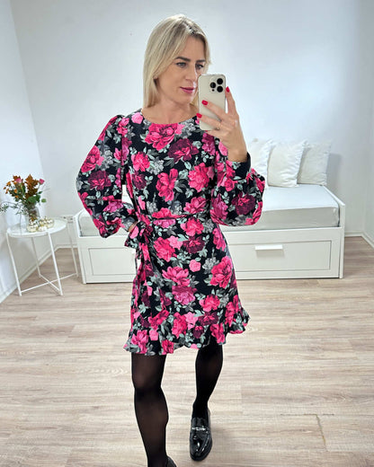 Model ist 160 cm groß und präsentiert der Langarm Rundhals Mini Wickel Kleid Marbella mit Rosen Print in der Größe S aus 70 % Viskose und 30 % Polyester. Foto auf weißen Hintergrund. Nella Fashion Shop 