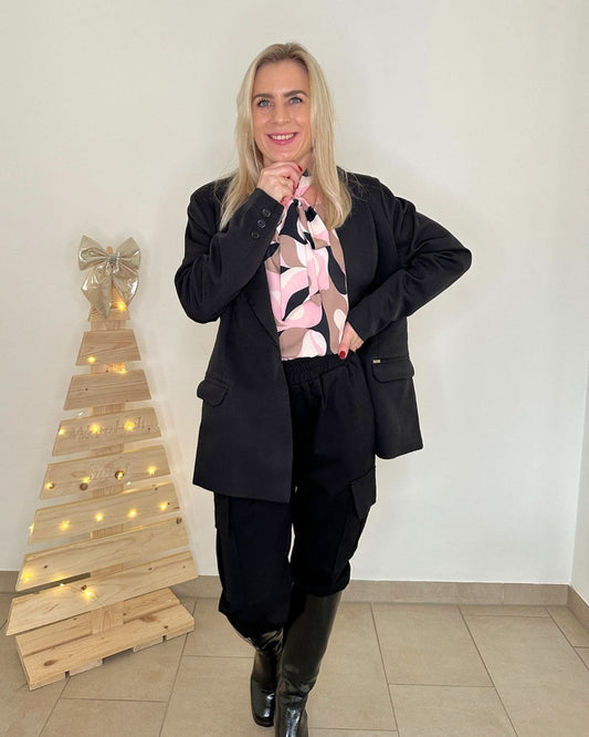 Model präsentiert den Damen Blazer Schwarz in 38 Größe kombiniert mit Hosen und Damen Bluse-Hemd, Langarm, mit Schleifenkragen, ein perfekter Still. Der Blazer ist Oversized mit 1-Knopf und Seitentaschen. Alles auf ein Weißenhintergrund. Nella Fashion Shop 