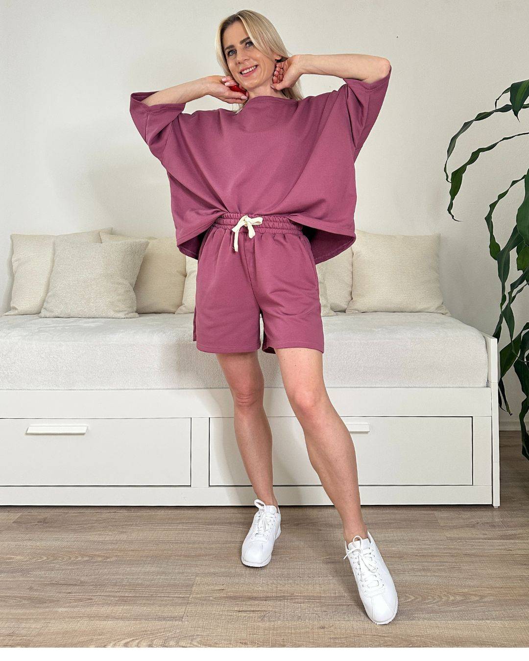 Model trägt den bequemen Damen lockeres Oversized T-Shirt mit weiten Armen in Beerenfarbe, Shorts mit Schnurdetail in Teile und Seitentaschen, Set ist in Einheitsgroesse XS bis XL von Nella Fashion Shop