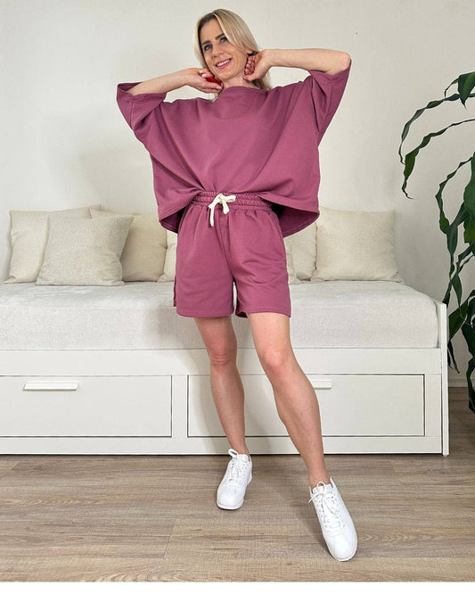 Model trägt den bequemen Damen lockeres Oversized T-Shirt mit weiten Armen in Beerenfarbe, Shorts mit Schnurdetail in Teile und Seitentaschen, Set ist in Einheitsgroesse XS bis XL von Nella Fashion Shop