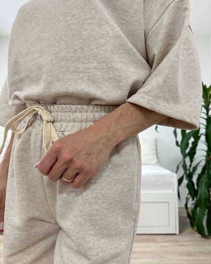 Model trägt den bequemen Damen lockeres Oversized T-Shirt mit weiten Armen in Beige, Shorts mit Weißen Schnurdetail in Teile und Seitentaschen aus 95 % Baumwolle, 5 % Polyester, Set ist in Einheitsgroesse XS bis XL von Nella Fashion Shop