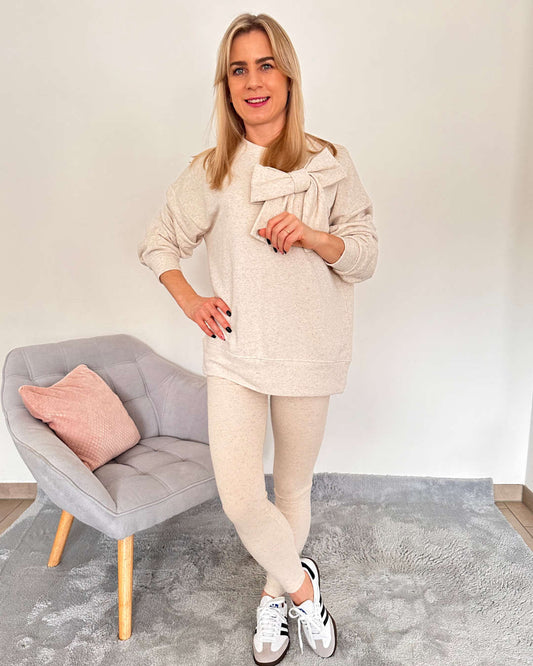 Dieses Model ist 160 cm groß und trägt Beige Oversized-Sweatshirts mit großer Schleife vorne in Einheitsgröße XS bis M kombinierbar mit den gerippten dehnbaren Leggings mit Gummi in der Teile bietet es einen bequemen, eleganten und sportlichen-look für den Alltag. Alles auf ein Weißenhintergrund, Nella Fashion Online Shop   