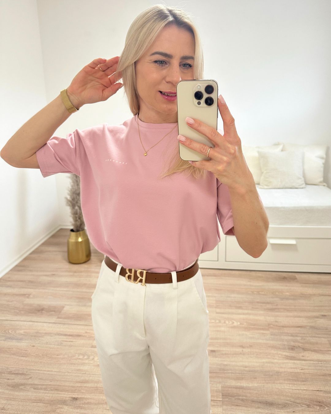 Model präsentiert das bequeme Rosa Rundhals Damen T-Shirt aus 95 % Baumwolle und 5 % Elastan, Größe XS bis L, dazu unsere Damenhosen in Ecru auf ein Weißenhintergrund, Accessoires: Gürtel, Handy, Armbanduhr, Nella Fashion Shop Onlineshop

