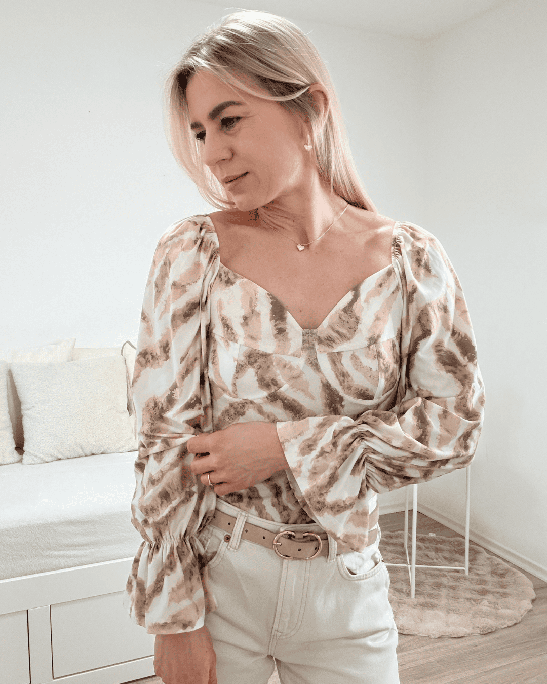 Model trägt die spanische Damenbluse mit Beige Zebra-Muster in der Größe S. Aus 60 % Polyester / 35 % Viskose / 5 % Elastan Mischung. Getragen als schulterfreien Oberteilen. Spanische Carmen-Bluse ist Langarm, mit einem Gummiband am Arm  angezogen und mit Rüsche beendet, dazu Gummiband an der Schulter und Brustumfang. Hintergrund Weiß. Jetzt bei Nella Fashion Shop Deutschland S und M Größe