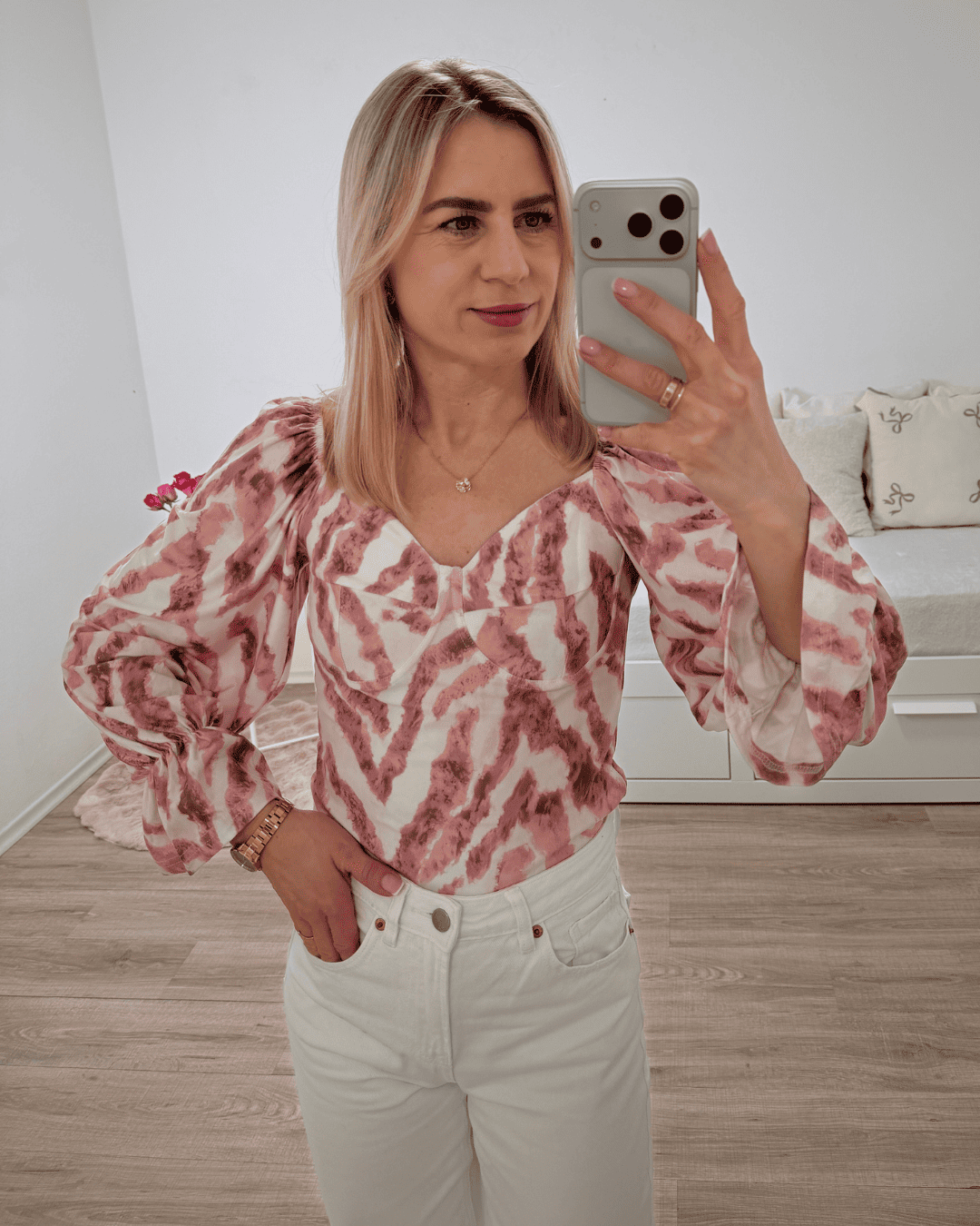 Model trägt die spanische Damenbluse mit Rosa Zebra-Muster in der Größe S. Aus 60 % Polyester / 35 % Viskose / 5 % Elastan Mischung. Getragen als schulterfreien Oberteilen. Spanische Carmen-Bluse ist Langarm, mit einem Gummiband am Arm  angezogen und mit Rüsche beendet, dazu Gummiband an der Schulter und Brustumfang. Hintergrund Weiß. Jetzt bei Nella Fashion Shop Deutschland S und M Größe