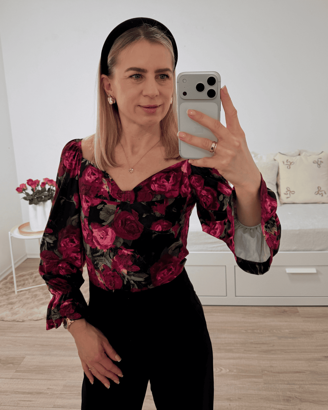 Model trägt die spanische Damenbluse mit roten Rosen-Muster in der Größe S. Getragen als schulterfreien Oberteilen oder V-Ausschnitt. Spanische Carmen-Bluse ist Langarm, mit einem Gummiband am Arm  angezogen und mit Rüsche beendet, dazu Gummiband an der Schulter und Brustumfang. Hintergrund Weiß. Jetzt bei Nella Fashion Shop Deutschland