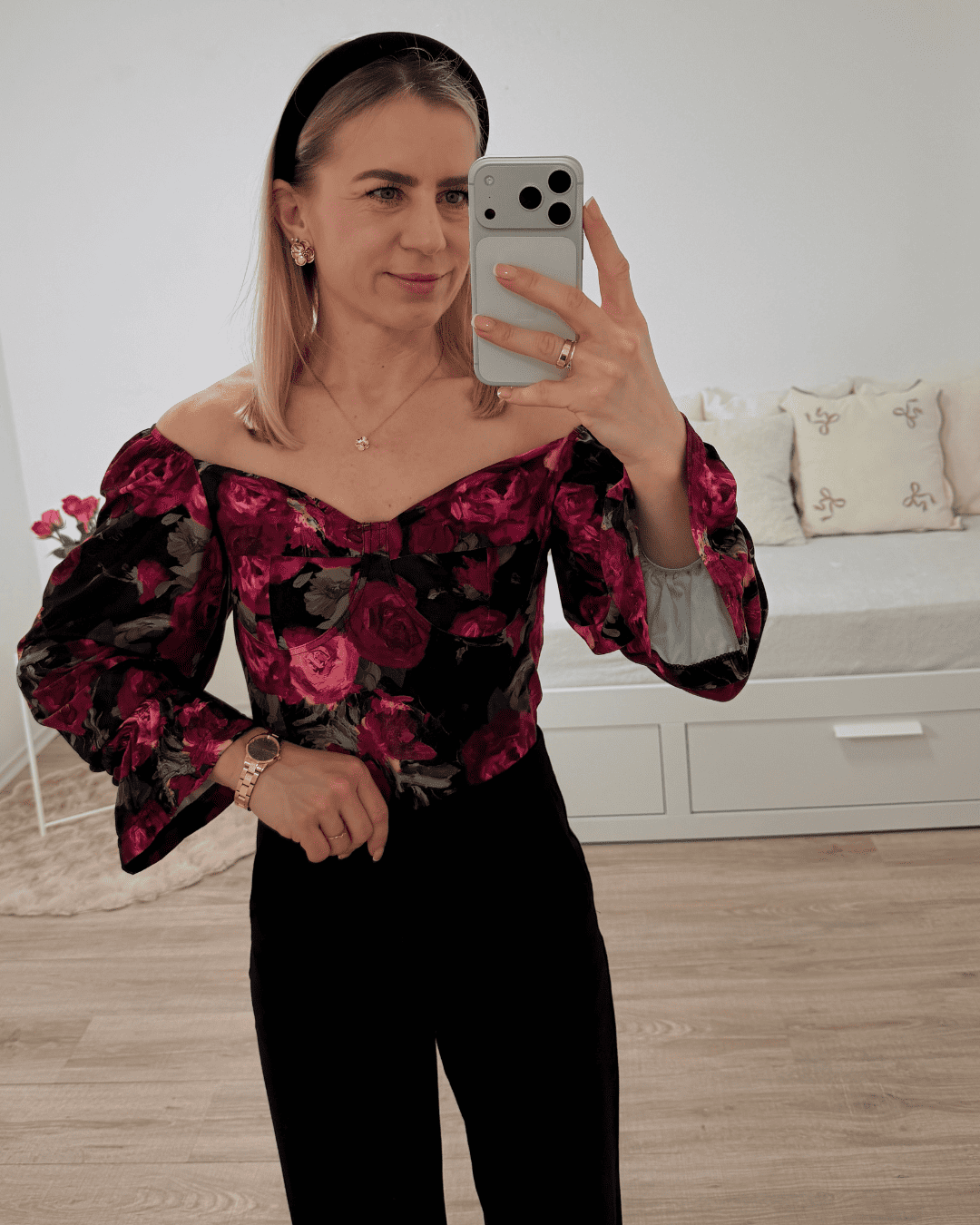 Model trägt die spanische Damenbluse mit roten Rosen-Muster in der Größe S. Aus 60 % Polyester / 35 % Viskose / 5 % Elastan Mischung. Getragen als schulterfreien Oberteilen. Spanische Carmen-Bluse ist Langarm, mit einem Gummiband am Arm  angezogen und mit Rüsche beendet, dazu Gummiband an der Schulter und Brustumfang. Hintergrund Weiß. Jetzt bei Nella Fashion Shop Deutschland S und M Größe