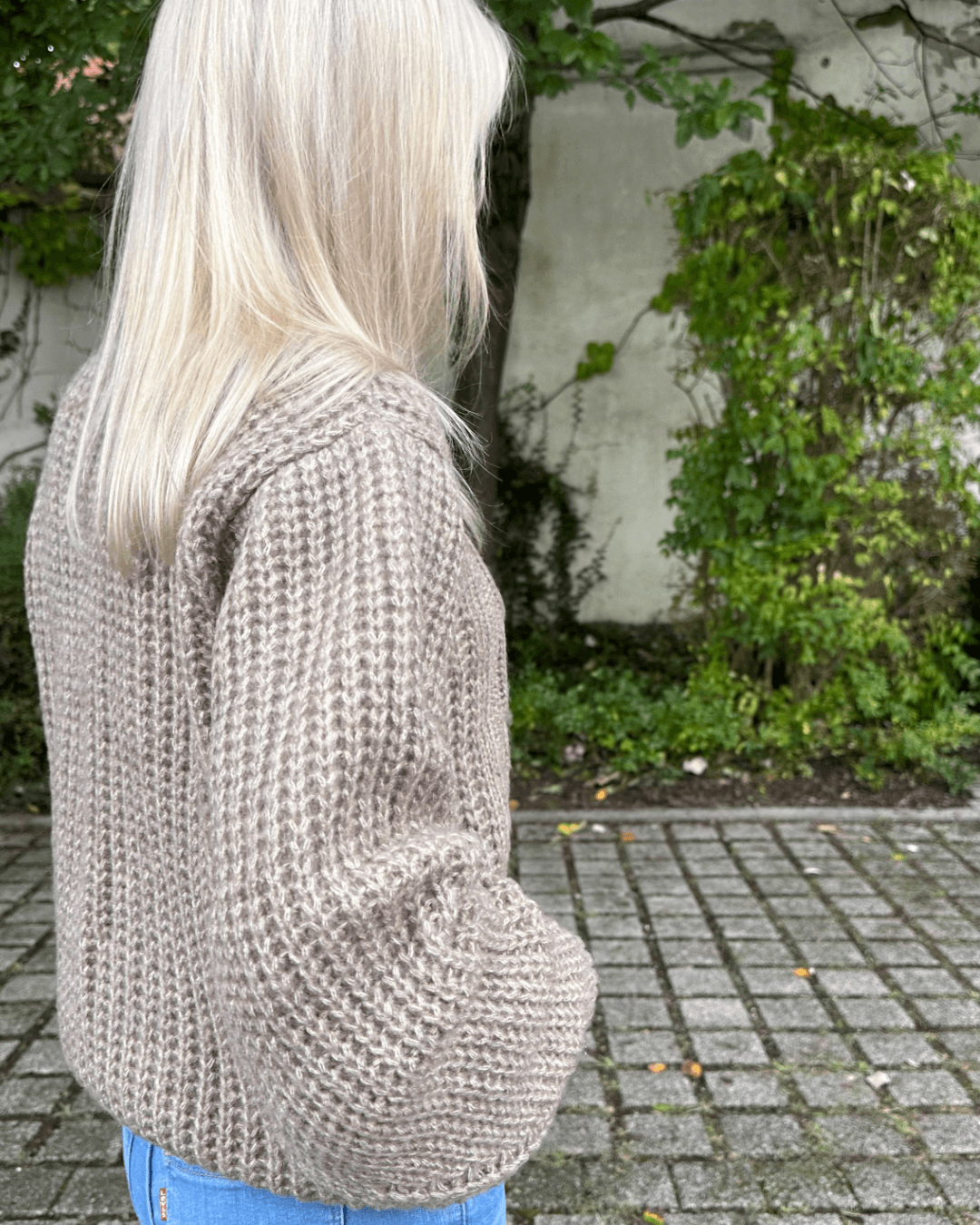 Model präsentiert bei Stehen in Park den Oversized-Strickpullover Rundhals mit Zopfmuster Langarm Einheitsgröße XS/L in Beige aus Materialien 15 % Mohair / 15 % Wolle / 10 % Polyester / 60 % Acryl. Erhältlich bei Nella Fashion Shop in Weiß, Dunkel beige, Schokoladenfarbe. 