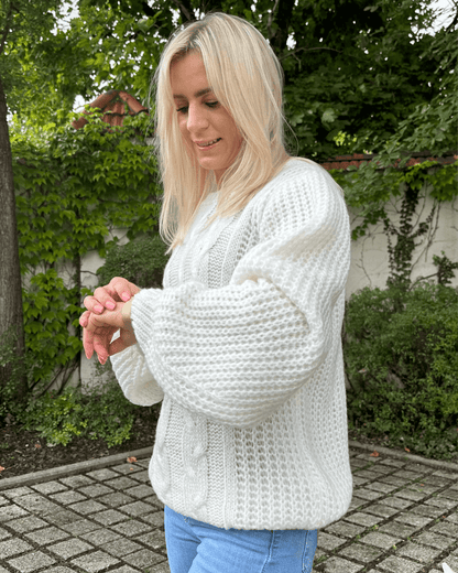 Model präsentiert bei Stehen in Park den Oversized-Strickpullover Rundhals mit Zopfmuster Langarm Einheitsgröße XS/L in Weiß aus Materialien 15 % Mohair / 15 % Wolle / 10 % Polyester / 60 % Acryl. Erhältlich bei Nella Fashion Shop in Weiß, Dunkel beige, Schokoladenfarbe. 